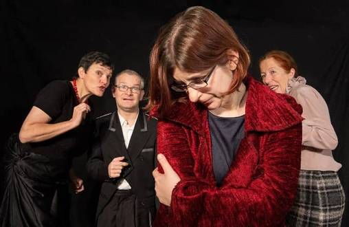 Quelle: Die Schattenspringer Eine Frau steht im Vordergrund mit dem Kopf nach unten, dahinter stehen andere Menschen und tuscheln.